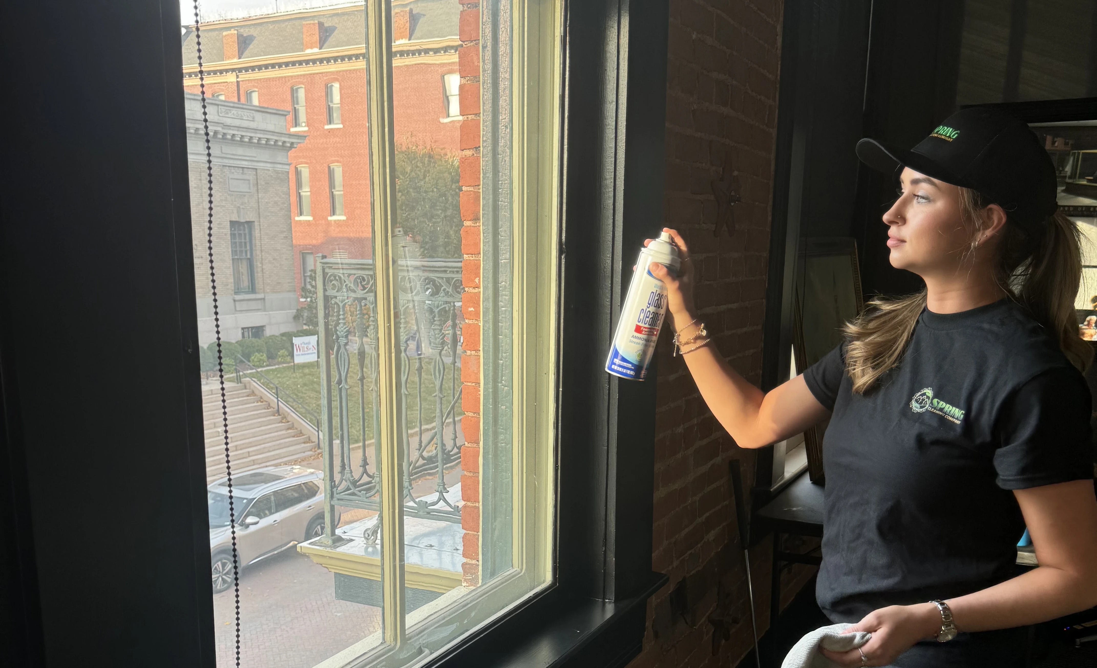 Spring Cleaning Company professional cleaning team member using spray bottle and rag to clean windows during commercial cleaning service in St. Charles, Missouri