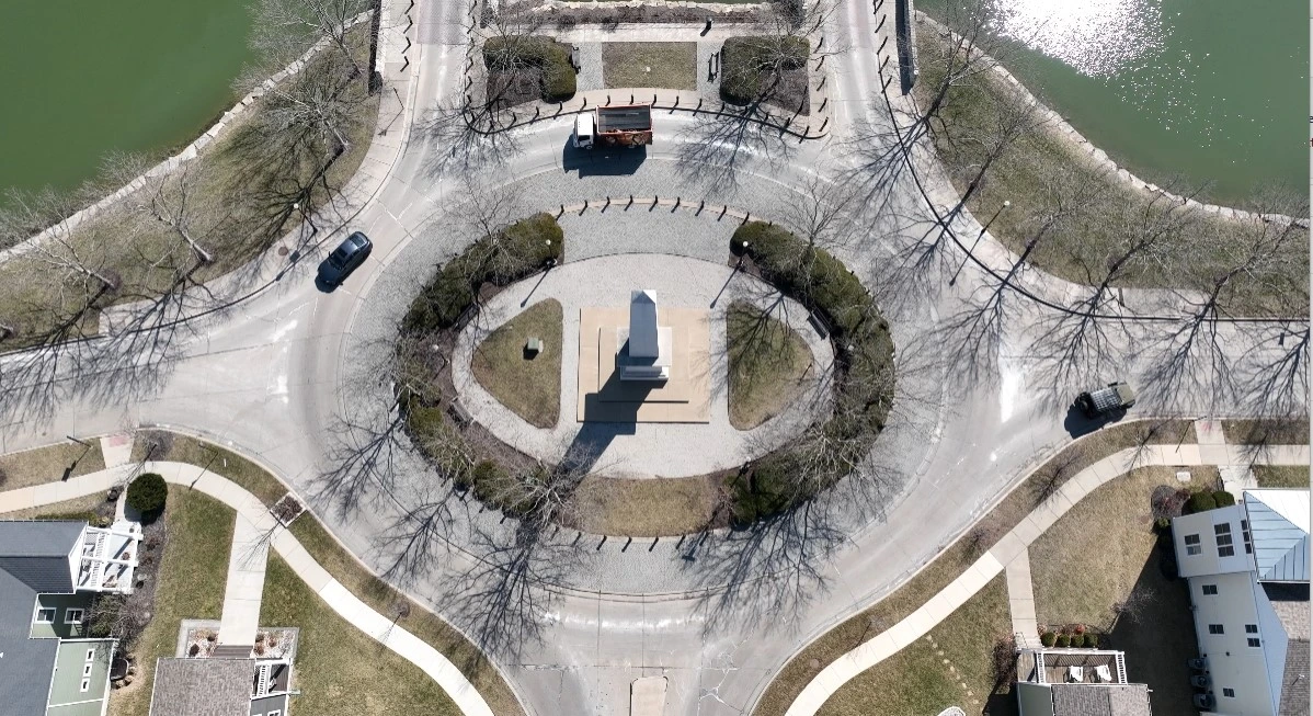 Aerial drone shot of New Town monument in St. Charles, Missouri with Spring Cleaning Company truck going around roundabout full of junk picked up after job