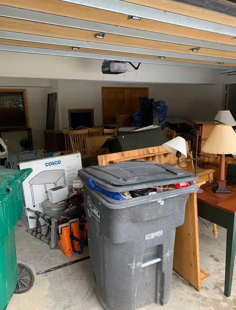 Trash can, chairs, tables, boxes, old lamps, and more in garage ready for Spring Cleaning Company residential junk removal in St. Louis, Missouri