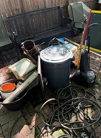 Patio piled with hoses, bins and junk before a JunkItNow.com cleanout