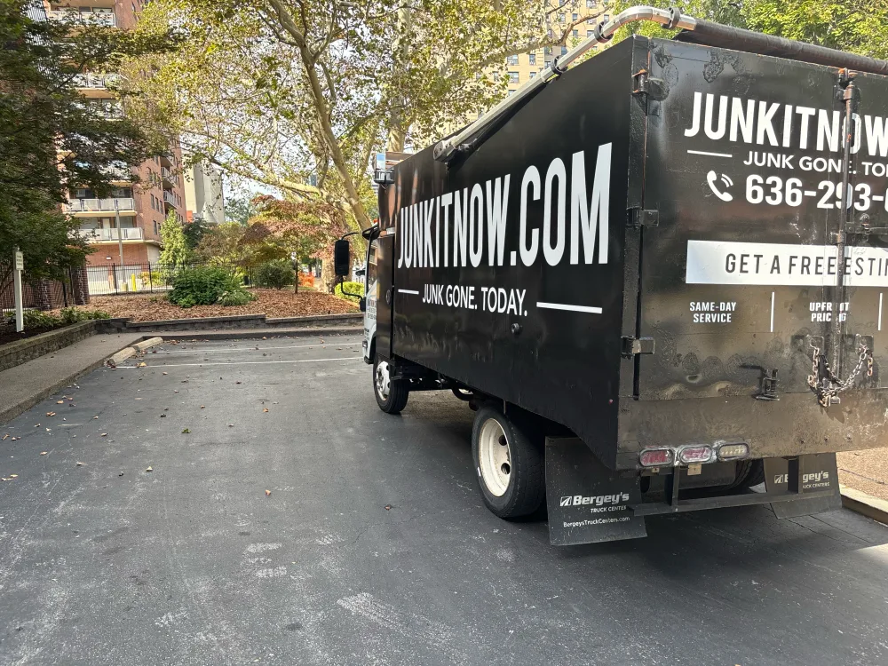 JunkItNow.com junk removal truck parked at an apartment community for a cleanout