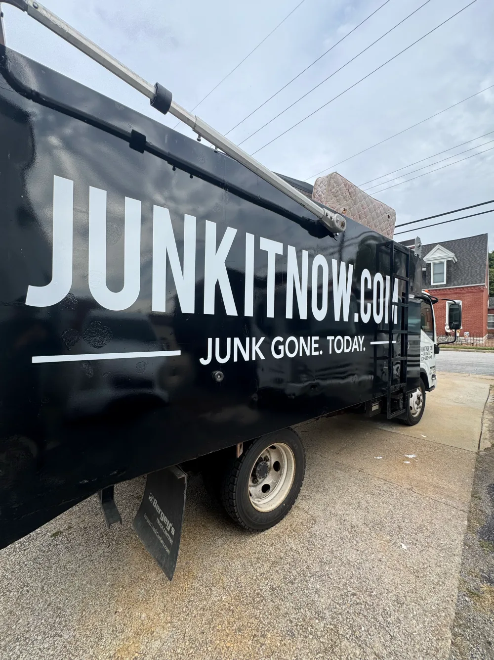 JunkItNow.com junk removal truck with a mattress loaded on a residential pickup