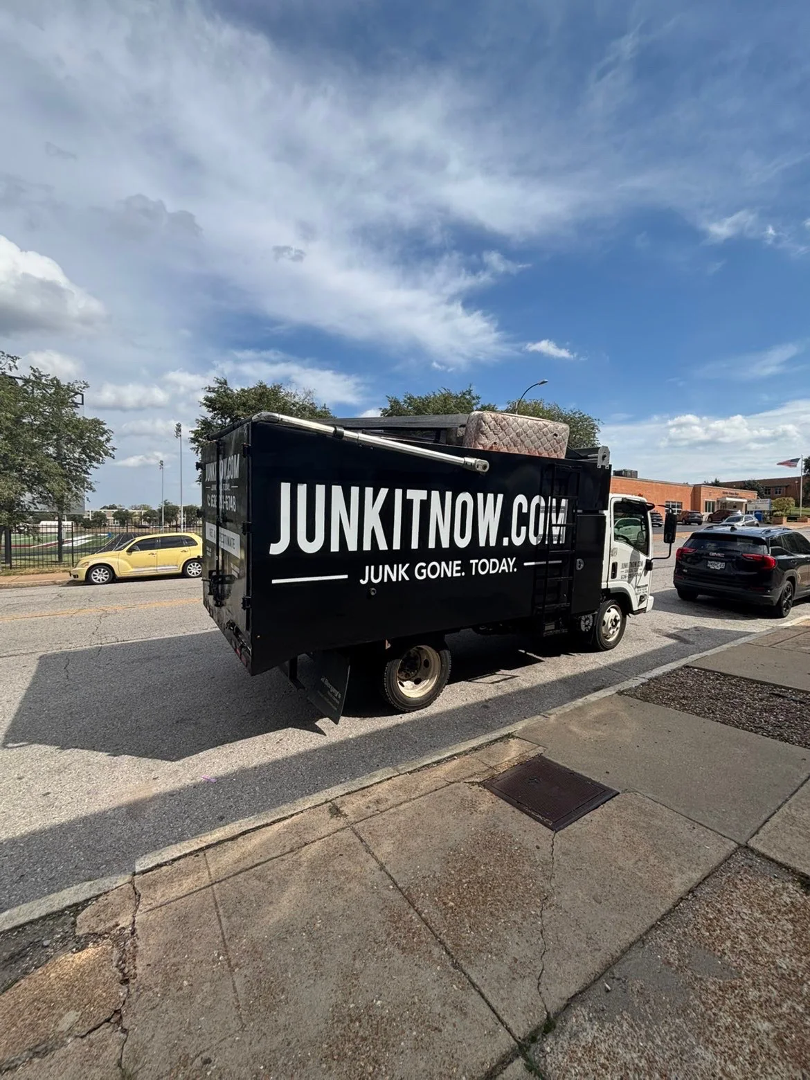 JunkItNow.com junk removal truck hauling a mattress on a St. Louis street